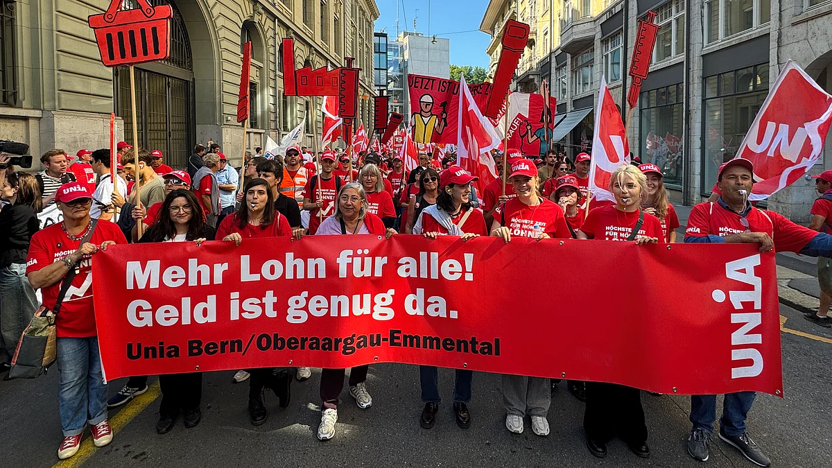 Demonstrationsblock der Unia Bern/Oberaargau-Emmental mit Pfeifen, Fahnen und einem roten Transparent mit der Aufschrift «Mehr Lohn für alle! Geld ist genug da.»
